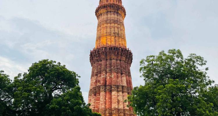 Qutub Minar entouré d'arbres au crépuscule.