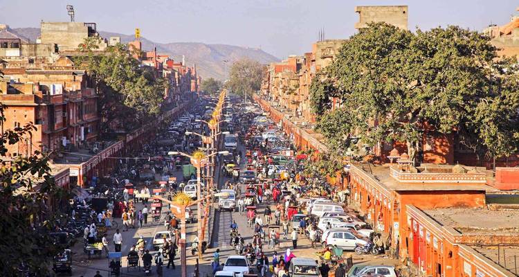 Rue animée à Jaipur avec des bâtiments roses historiques.