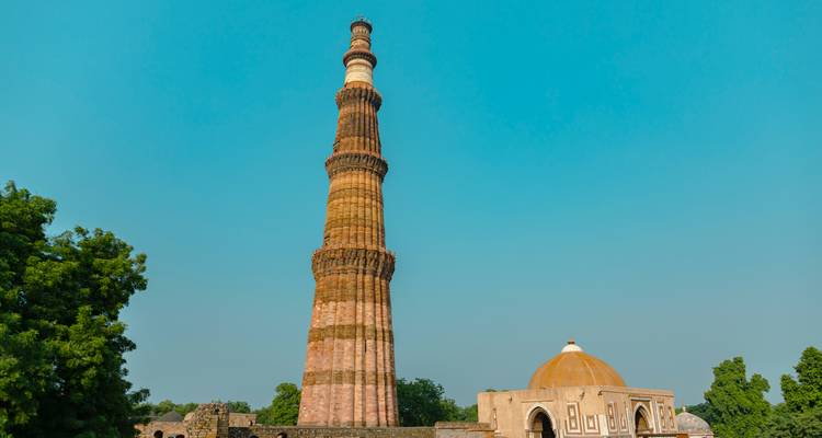 Un minaret historique élancé et un dôme se dressent contre un ciel dégagé.