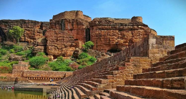 Ancien réservoir à gradins et structures rocheuses dans un site historique.