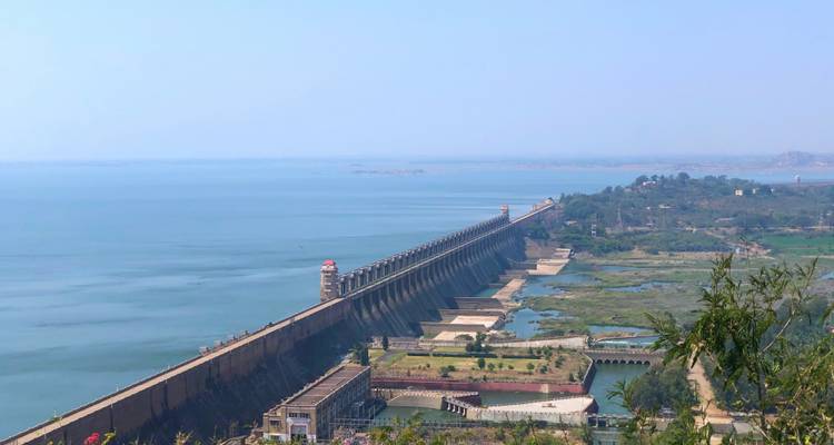 Un grand barrage au-dessus d'une large vallée vu de loin.