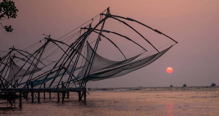 Filets de pêche contre un coucher de soleil au-dessus d'un plan d'eau.