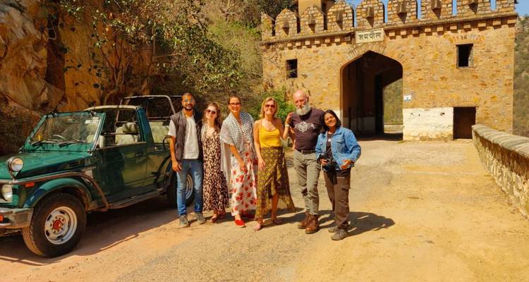 A group of tourists and a jeep near a historic gate.