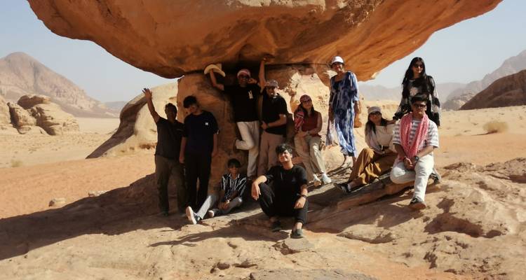 Groupe de personnes posant sous une formation rocheuse dans le désert.