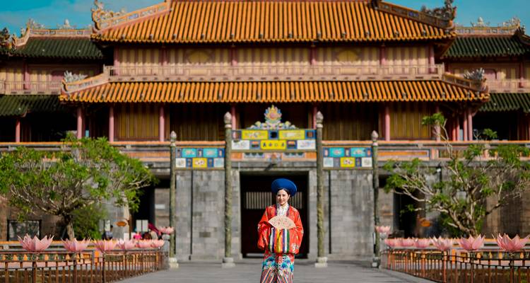 Person in traditional attire in front of Imperial City in Hue.
