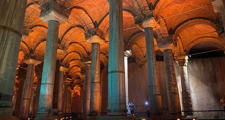 Zwak verlichte binnenkant van de Basilica Cistern met hoge zuilen die weerspiegeld worden in ondiep water.
