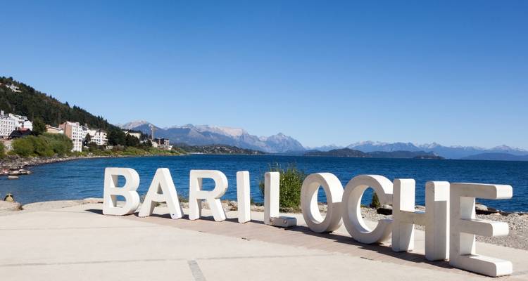 Letras grandes que deletrean 'BARILOCHE' junto a un lago con montañas.