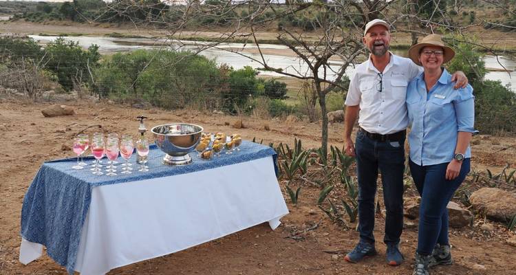 Zwei Personen stehen neben einem Tisch mit Getränken, Außenbereich.