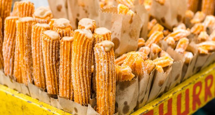 Rows of freshly made churros in paper bags.