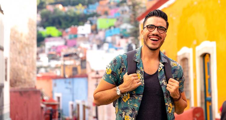 Smiling man in a colorful street setting.