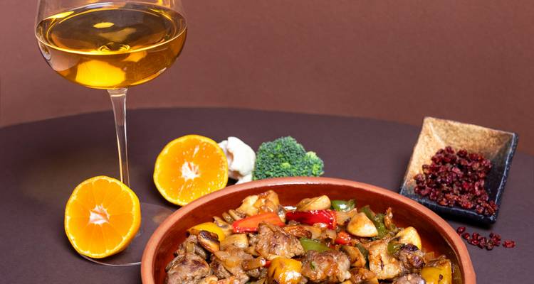 Plat de ragoût de poulet avec légumes et un verre de vin sur une table.