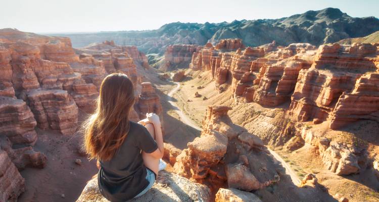 Persona sentada en acantilados con vista a los cañones.