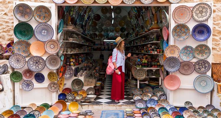 Frau kauft bunte Keramik auf einem Markt ein.