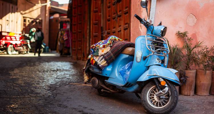 Blauer Roller mit bunten Decken bedeckt in enger Straße.