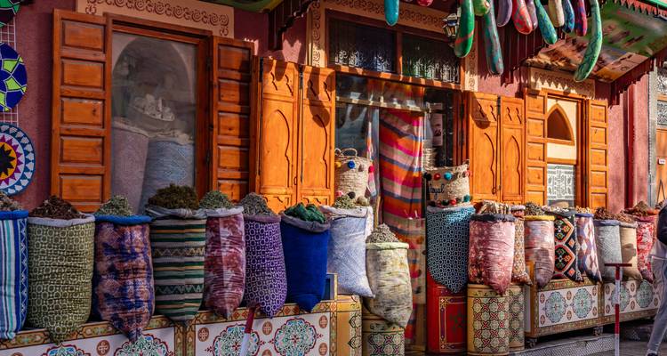 Bunter Marktstand mit Säcken voller Kräuter und Stoffe.