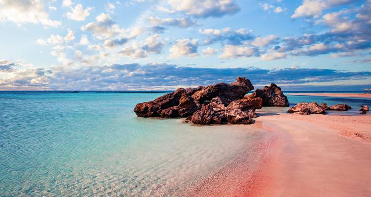 Scenic beach with turquoise water and rocks, under a cloudy sky.