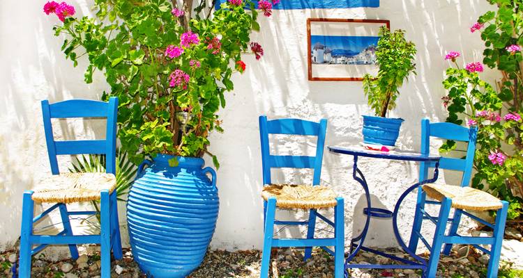 Blue chairs and table with flowers against white walls.