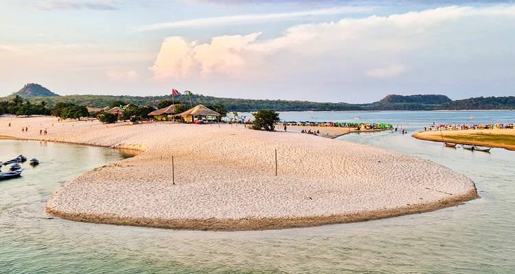 Malerischer Blick auf einen Sandstrand mit Hütten und ruhigem Wasser.
