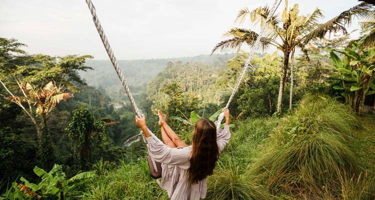 Personne se balançant haut au-dessus d'un décor de jungle verdoyante et luxuriante.