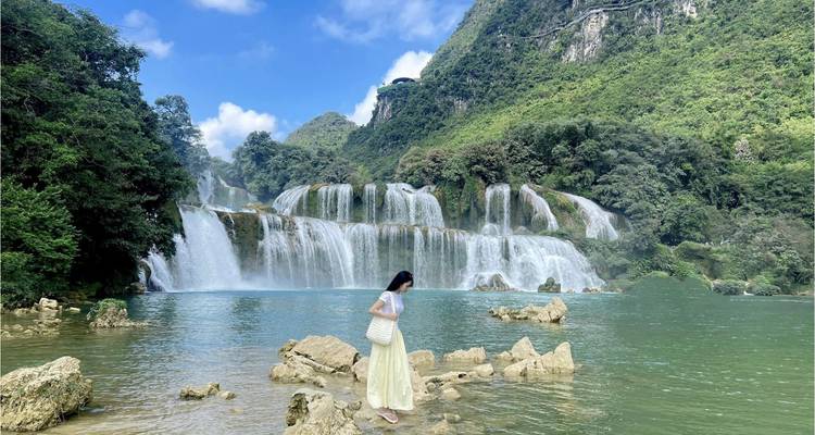 Cascade avec une femme au premier plan sur des rochers.
