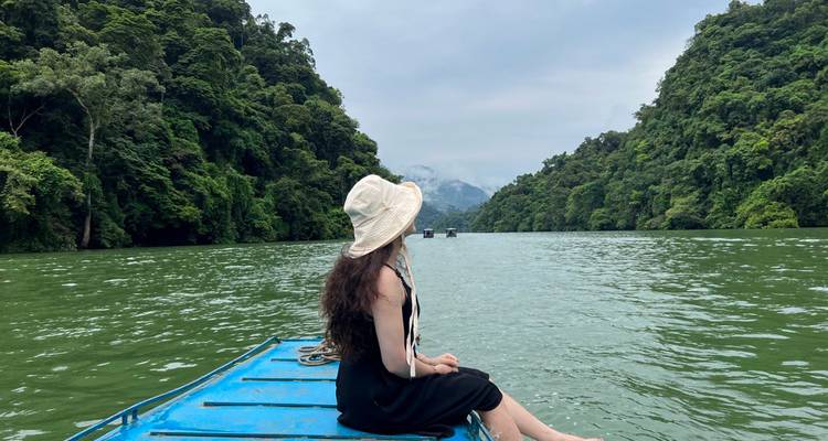 Femme assise sur un bateau regardant une rivière et un paysage forestier.