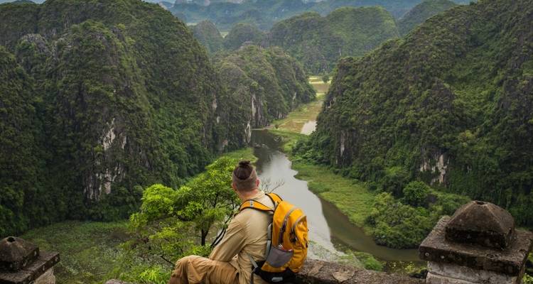 Personne assise à un point de vue surplombant une vallée et une rivière.