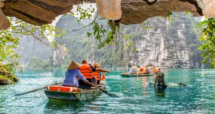 Des gens sur des bateaux explorant une grotte turquoise.