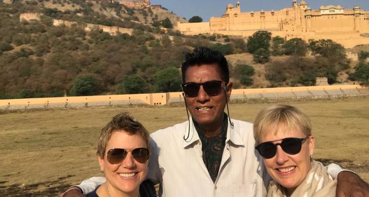 Three people smiling with a fort in the background