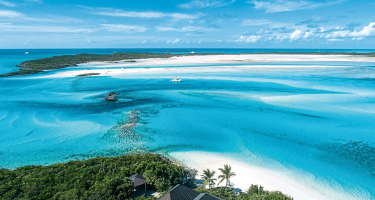 Sandy beaches and clear blue waters with a yacht.