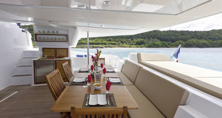 Luxury yacht deck set up for dining with sea view.