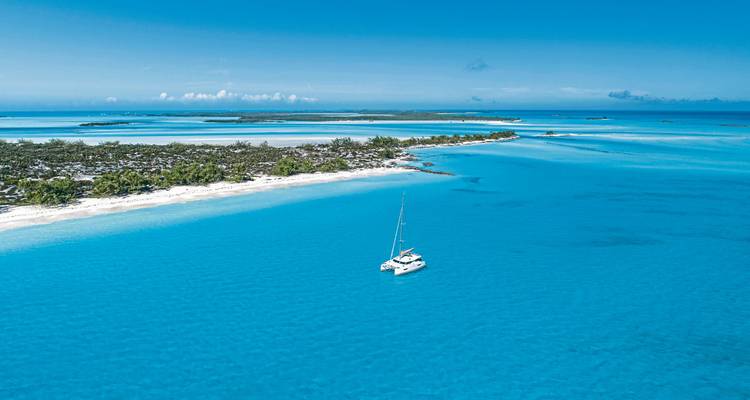 Secluded beach and clear blue waters with a yacht.