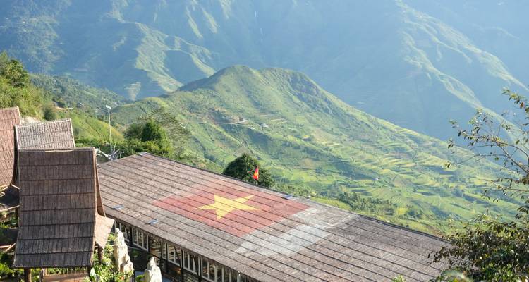 Dak met een groot Vietnamees vlag erop geschilderd met uitzicht op terrasgewijze heuvels die in het middaglicht baden, vlakbij Sapa.