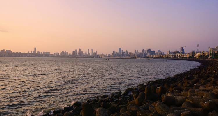 Amplia vista del horizonte de Mumbai a través del Mar Arábigo durante una puesta de sol brumosa.