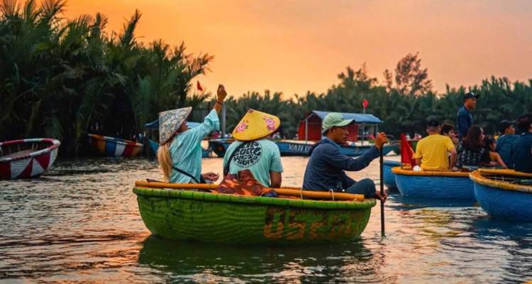 People in traditional boats on a river at sunset.