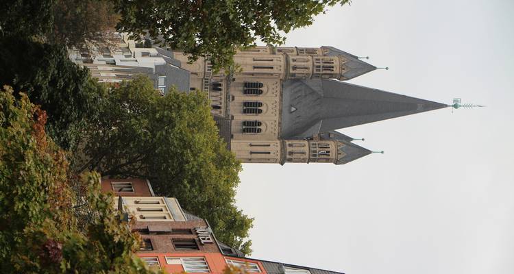 Tour d'église historique entourée d'arbres et de bâtiments.