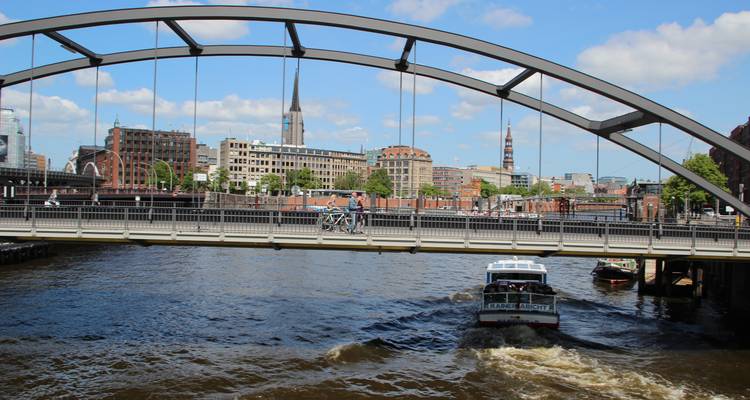 Bateau passant sous un pont moderne dans un paysage urbain.
