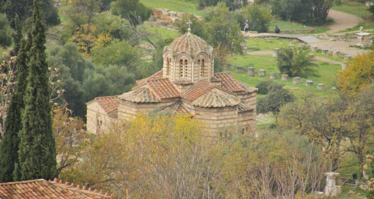 Small stone church surrounded by trees in a lush setting.