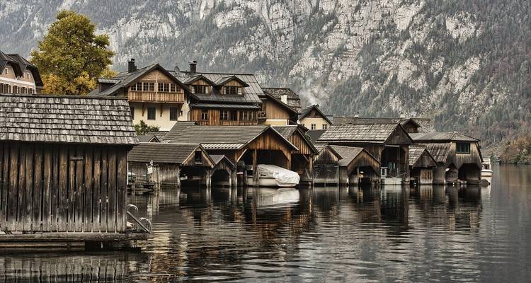 Lac avec des hangars à bateaux en bois sur fond de montagnes.