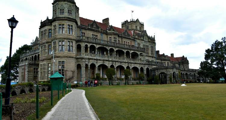 Large historic building with visitors, overcast sky.