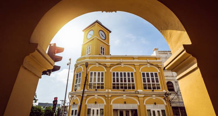 A historic yellow building with a clock tower viewed through an archway.