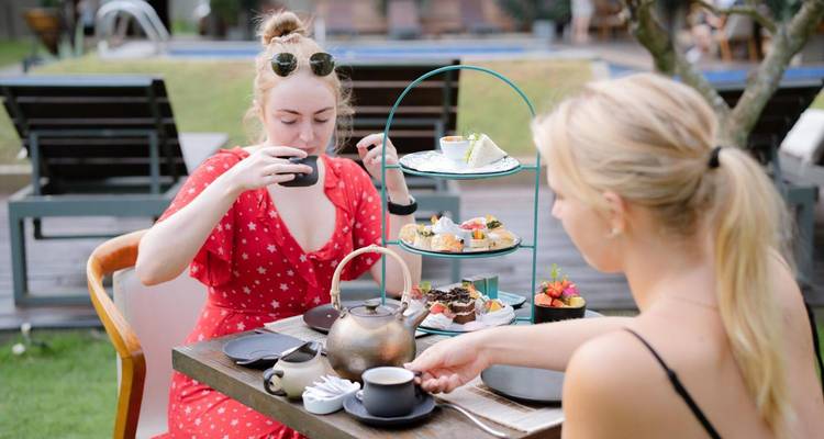 Two women having afternoon tea at an outdoor table.