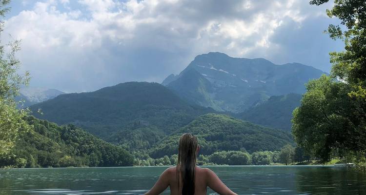 A woman swimming in a lake with a view of distant mountains.