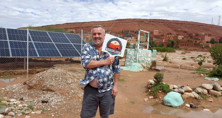 Man holding a sign in a rural area with solar panels.