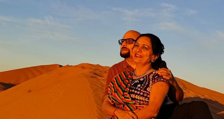 Couple sitting on a dune at sunset in the desert.