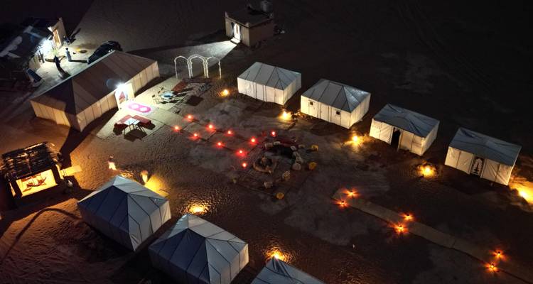 Vue aérienne d'un campement du désert bien éclairé la nuit.
