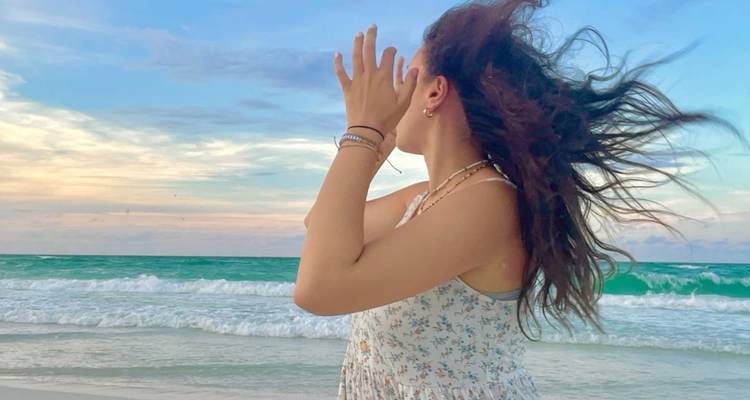 Woman on the beach looking at the ocean waves.