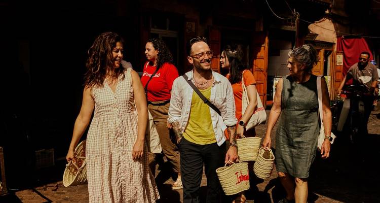 Viajeros cargando canastas tejidas explorando juntos las calles vibrantes de Marrakech.