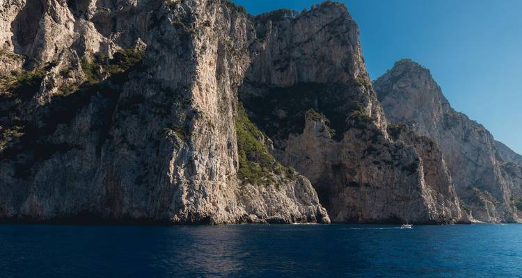 Côte rocheuse avec des falaises abruptes et une mer bleue sous un ciel clair.