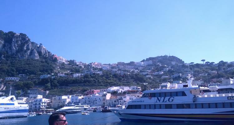 Passengers on ferries with a town on the hill in the background.