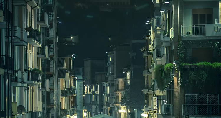 Une scène de nuit d'une rue entre des bâtiments résidentiels.